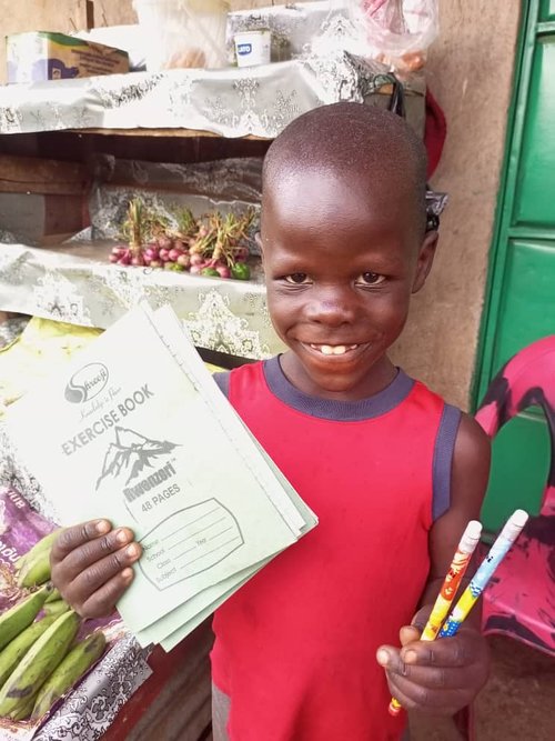 Smiling child holding exercise books and pens